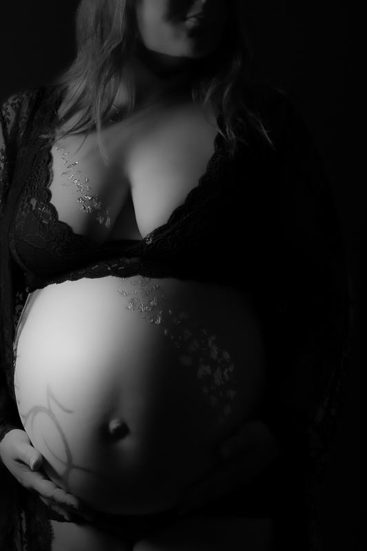 Frau mit Babybauch im schwarzen Zweiteiler aus Spitze