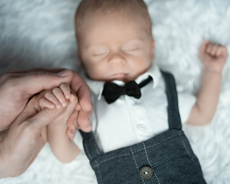 Neugeborenes Baby in Latzhose, Hemd und Fliege