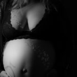 Frau mit Babybauch im schwarzen Zweiteiler aus Spitze