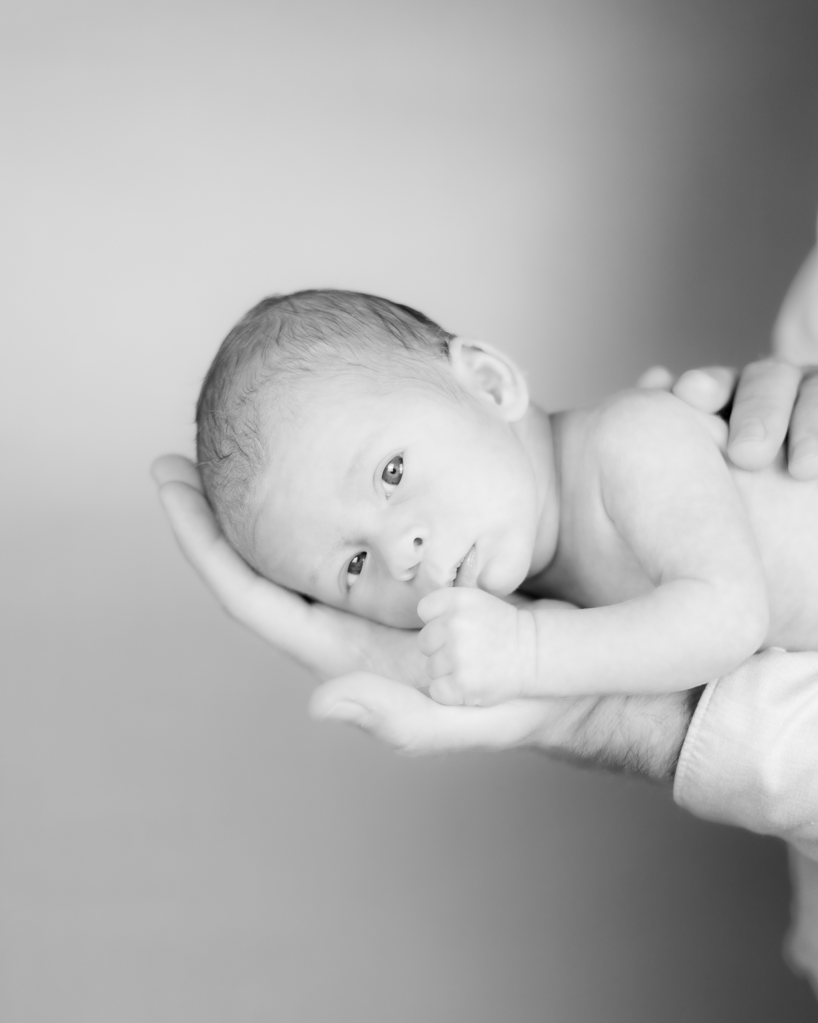 Neugeborenes Baby liegt auf Papas Arm