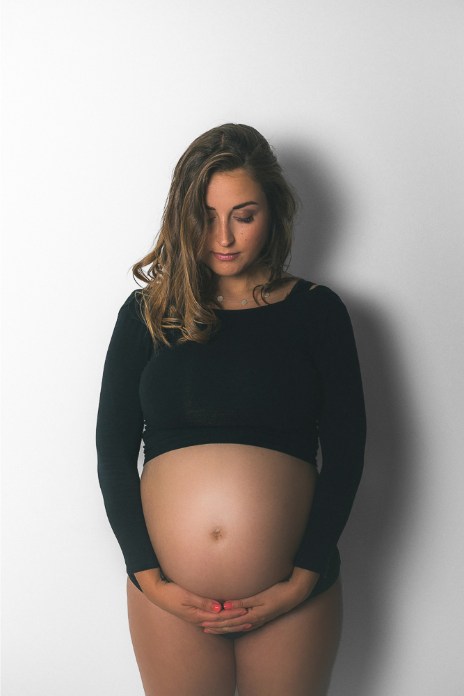 Frau mit Babybauch und schwarzem Zweiteiler