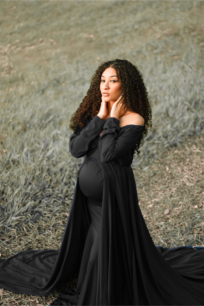Frau mit Babybauch im schwarzen Babybauchkleid während eines Babybauch-Shootings in der Natur in Wolfsburg