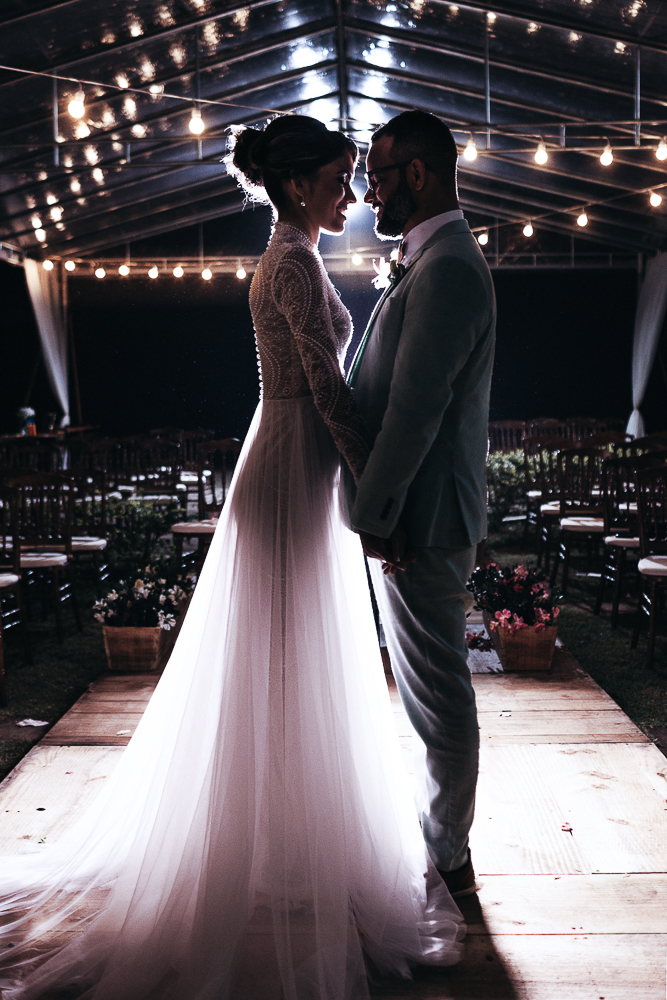 Brautpaar mit zweiteiligem Brautkleis im Fit an Flamme Stil auf der Hochzeit am Abend im Licht indirekt beleuchtet.